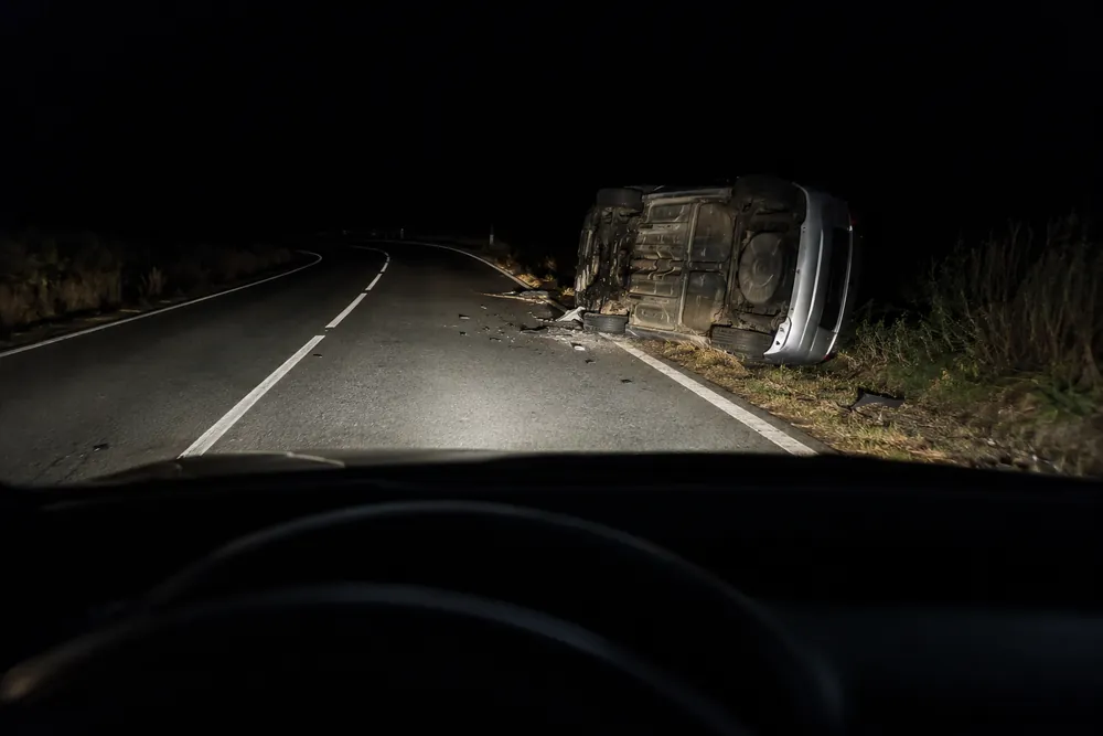 Accidente de noche en una carretera sin iluminación, visto con los faros del coche que llega.