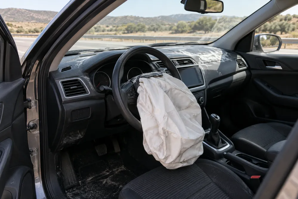 Interior de un turismo con el airbag del volante desplegado tras un golpe leve.