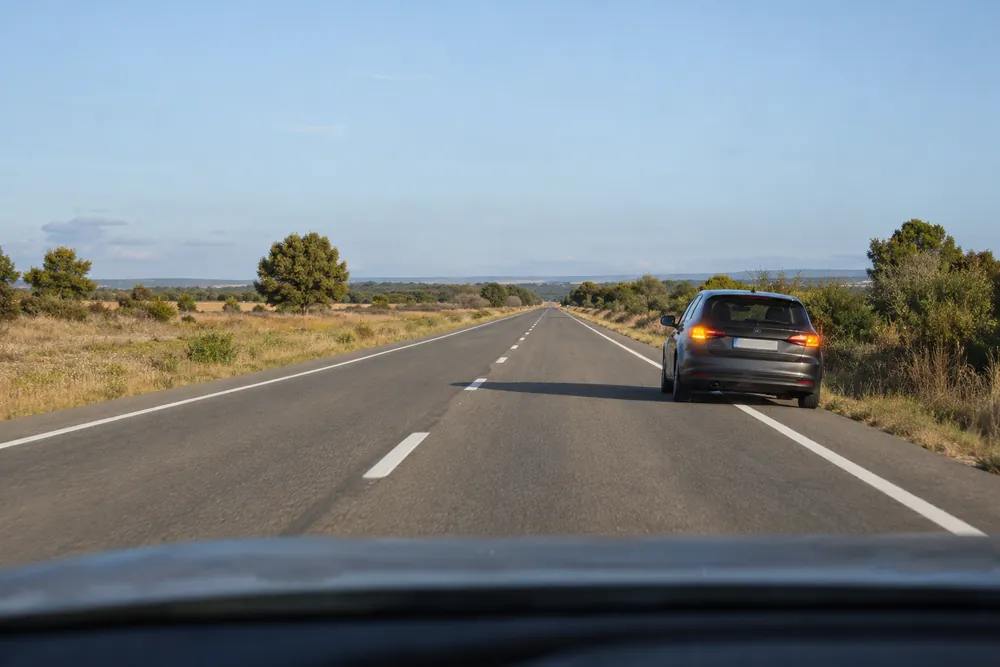 Turismo averiado en el carril propio de una recta con sentido contrario despejado.