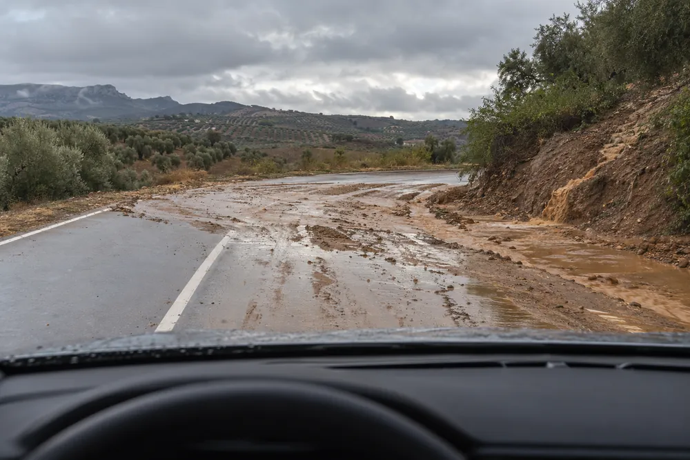 Barro arrastrado por la lluvia cubriendo una curva de carretera.