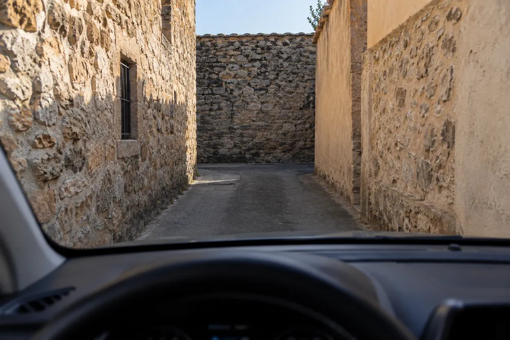 Calle estrecha cerrada por un muro que no permite girar el coche.