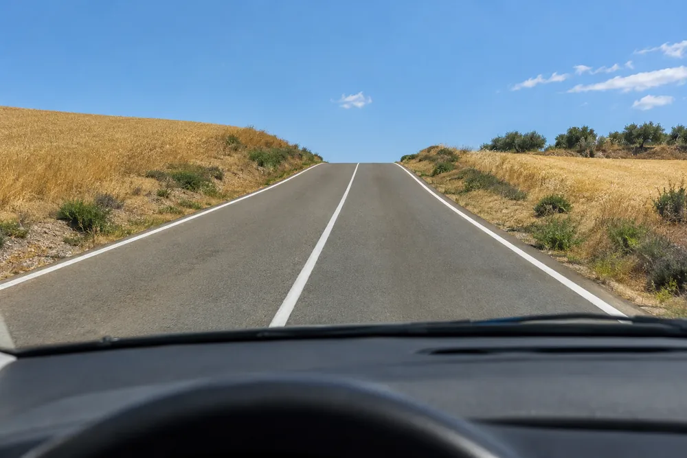 Carretera convencional que sube hacia un cambio de rasante tras el que no se ve nada.