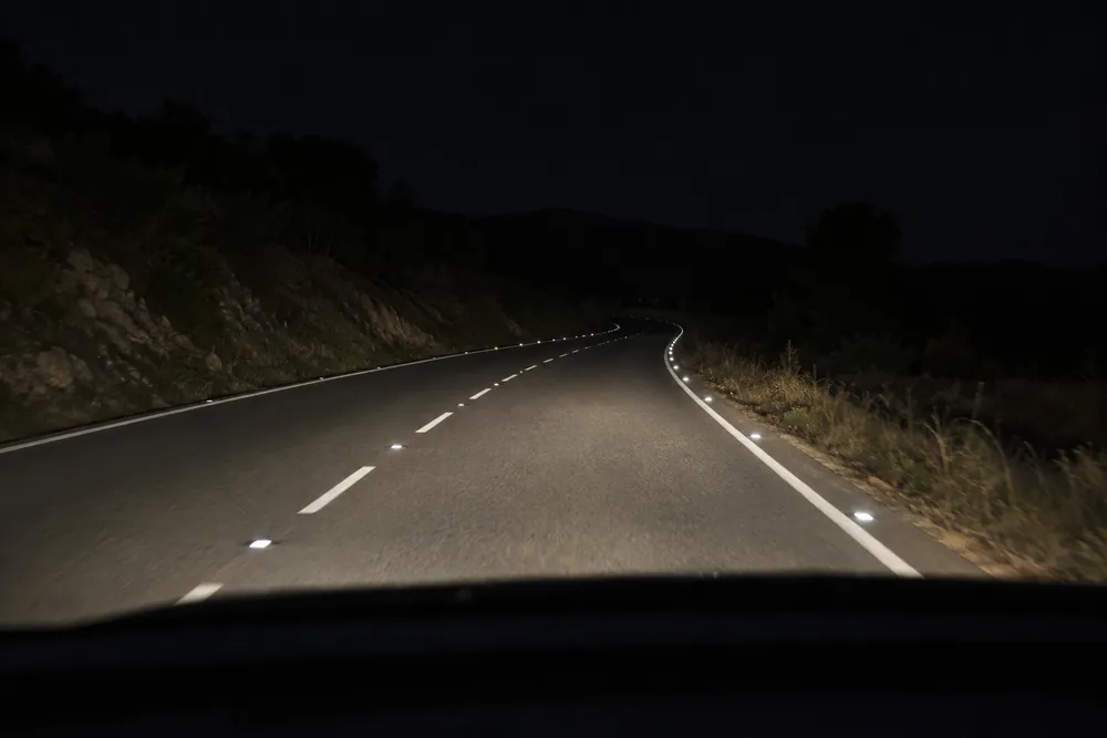 Captafaros incrustados en la calzada brillando de noche con los faros.
