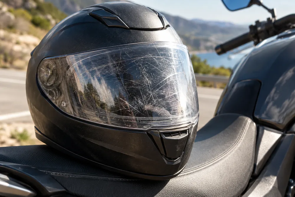 Pantalla transparente de casco de moto con numerosas rayas que dificultan ver a través.