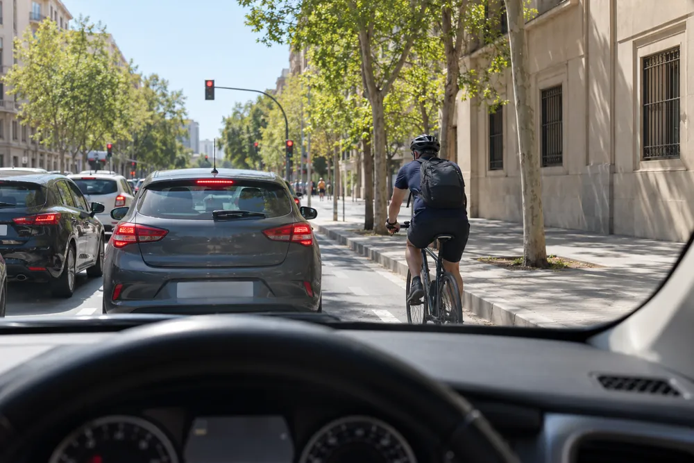 Ciclista rebasando por la derecha a los coches detenidos ante un semáforo en rojo.