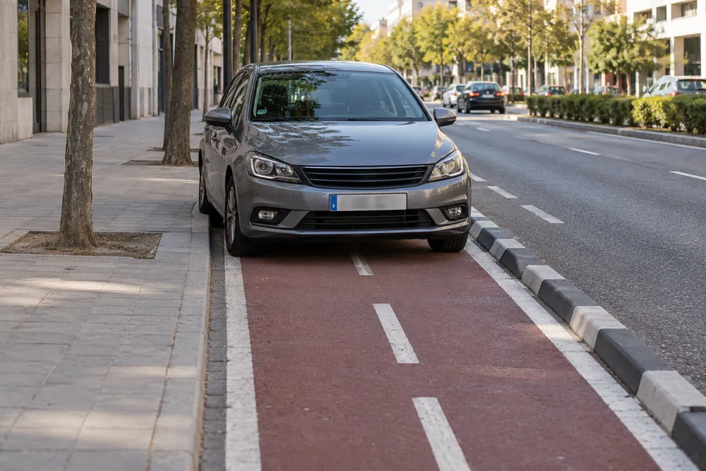 Turismo detenido ocupando completamente un carril bici urbano.