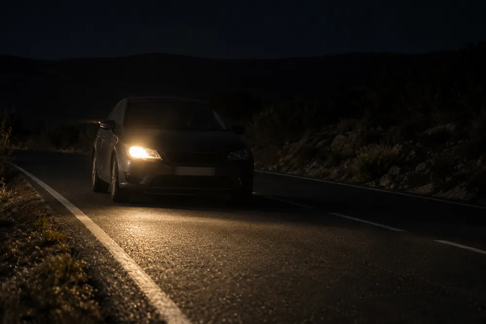 Turismo de noche que circula de frente con un solo faro encendido.