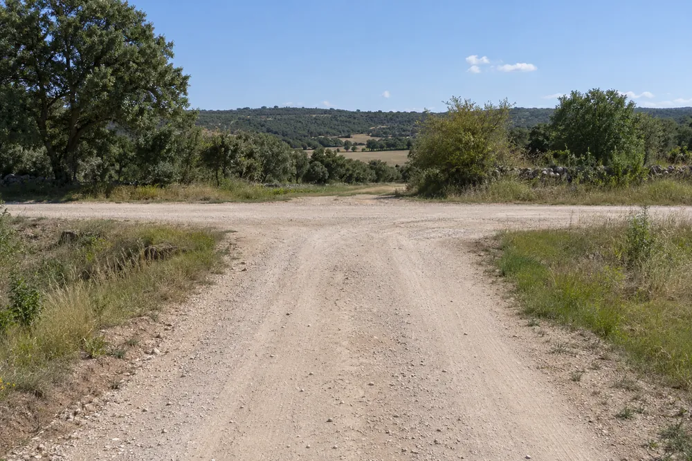 Dos caminos de tierra se cruzan sin señales, vistos desde uno de los accesos.