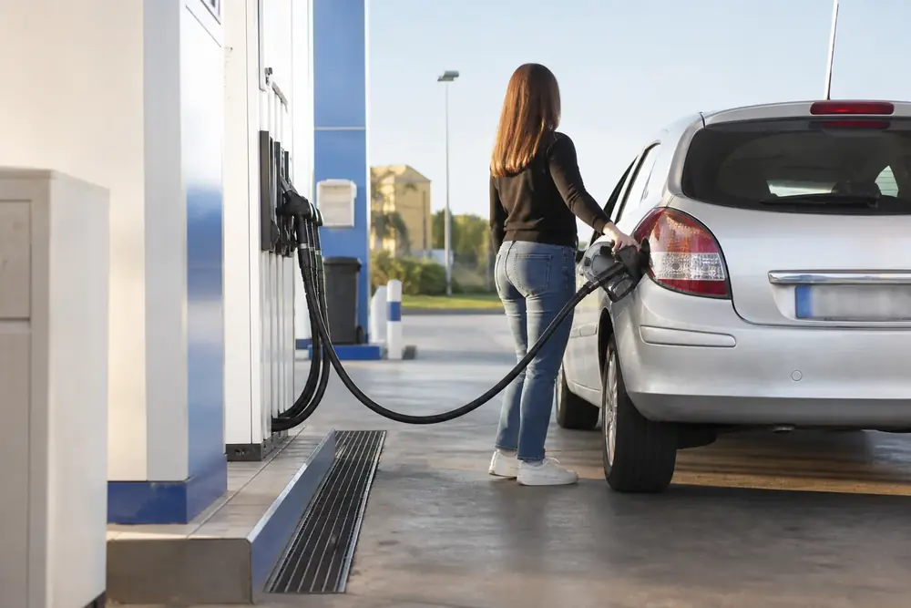 Persona repostando combustible en una estación de servicio