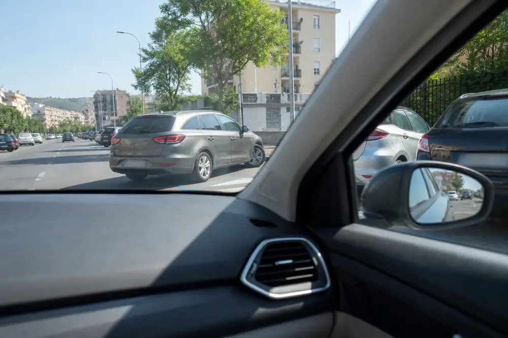 Retrovisor exterior y ventanilla desde el interior del coche en ciudad