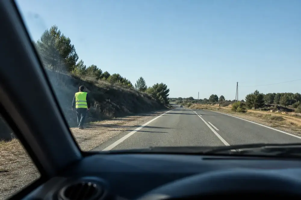 Peatón con chaleco reflectante caminando por el arcén, visto desde el coche