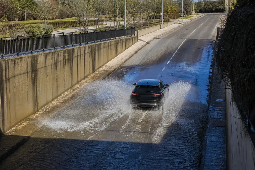Coche atravesando una lámina de agua en la calzada y levantando cortina