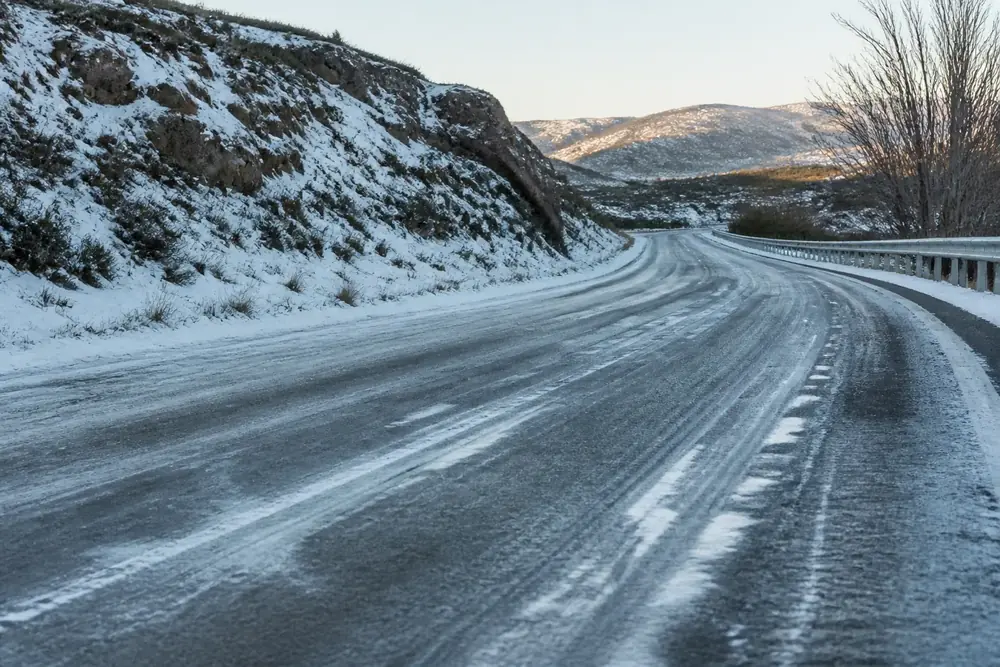 Carretera de montaña cubierta de nieve con roderas marcadas
