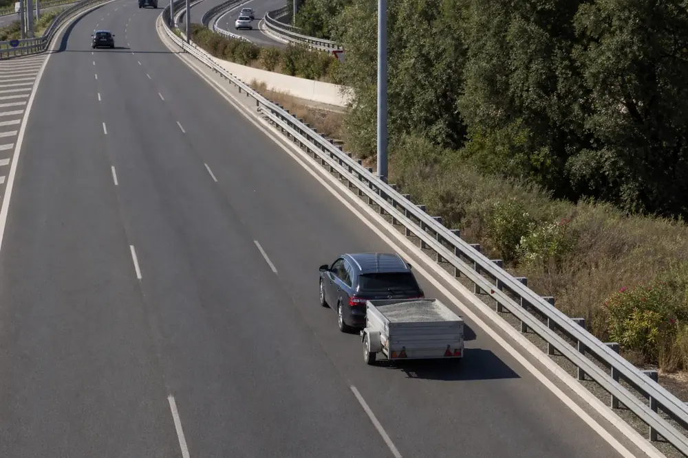 Coche con remolque circulando por autovía visto desde un puente