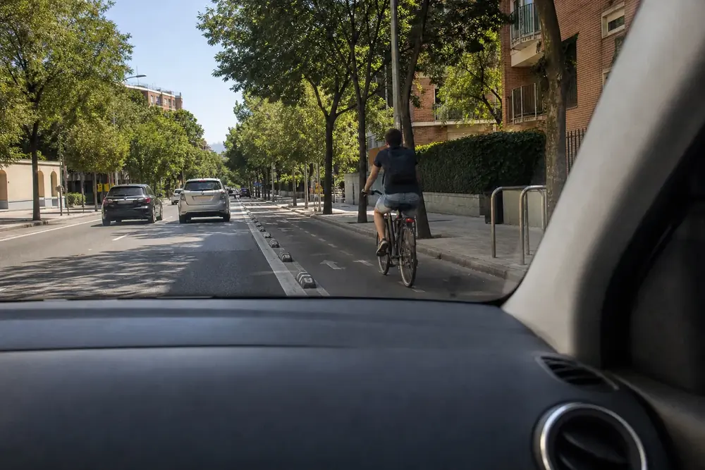 Ciclista por el carril bici a la derecha visto desde el puesto de conducción