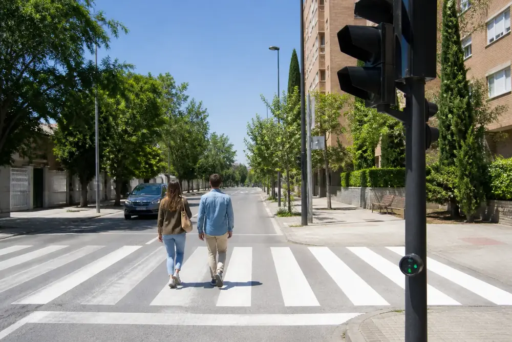 Pareja de peatones cruzando por un paso de cebra regulado por semáforo