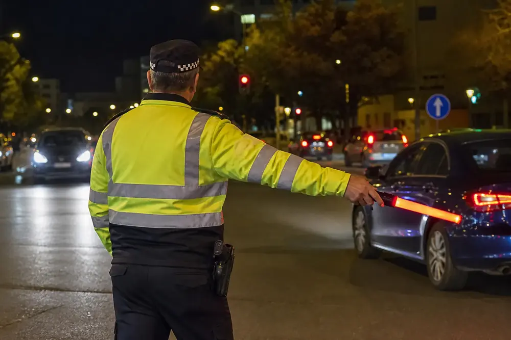 Agente dando el alto de noche con una linterna de señalización