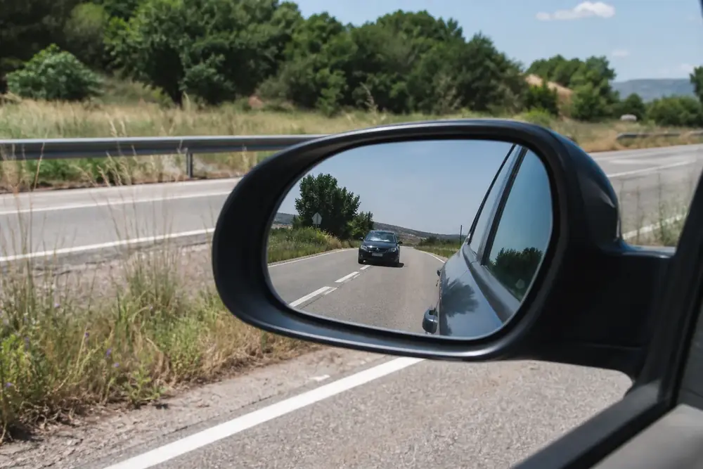 Vehículo que se acerca por detrás reflejado en el retrovisor exterior