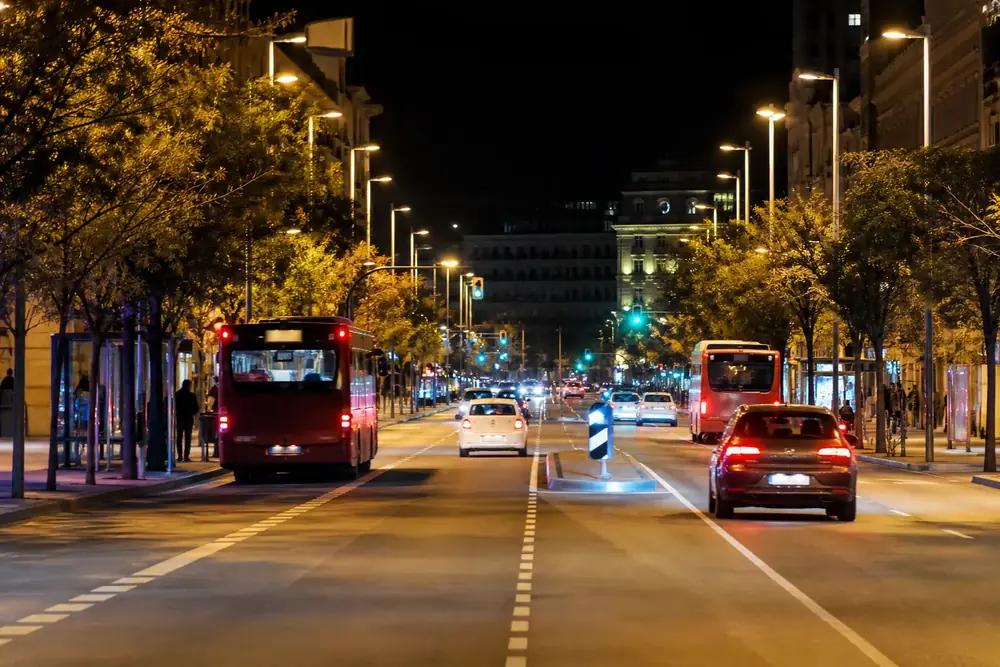 Avenida urbana de noche con autobuses y alumbrado