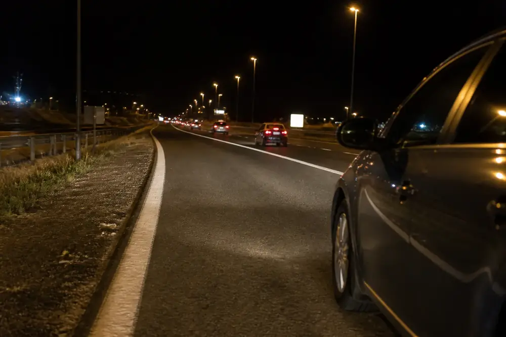 Carretera de noche con un vehículo circulando por delante