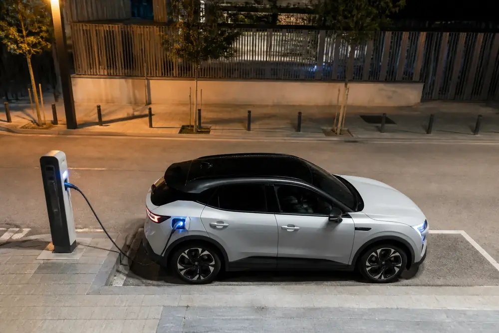 Vehículo eléctrico cargando de noche en una plaza reservada