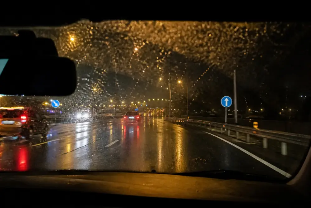 Conducción bajo la lluvia de noche con el parabrisas cubierto de gotas