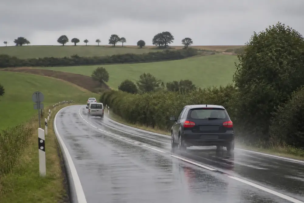 Carretera convencional mojada con un vehículo levantando agua