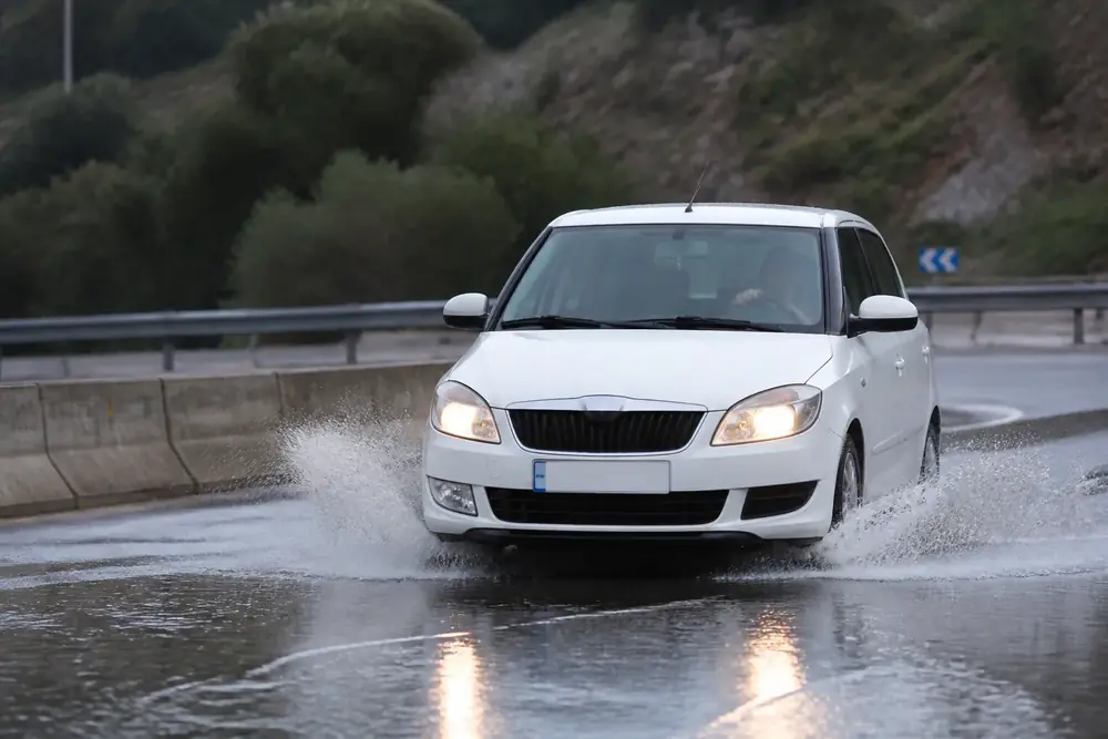 Turismo atravesando agua acumulada en la calzada