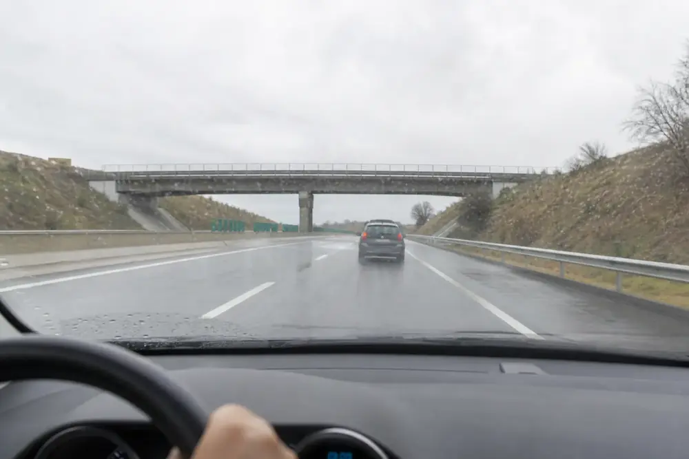 Conducción por autovía mojada con un vehículo por delante