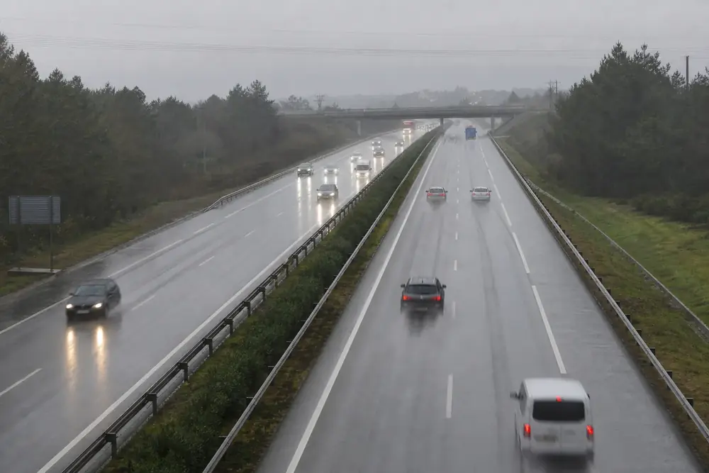 Autovía con lluvia y vehículos con las luces encendidas