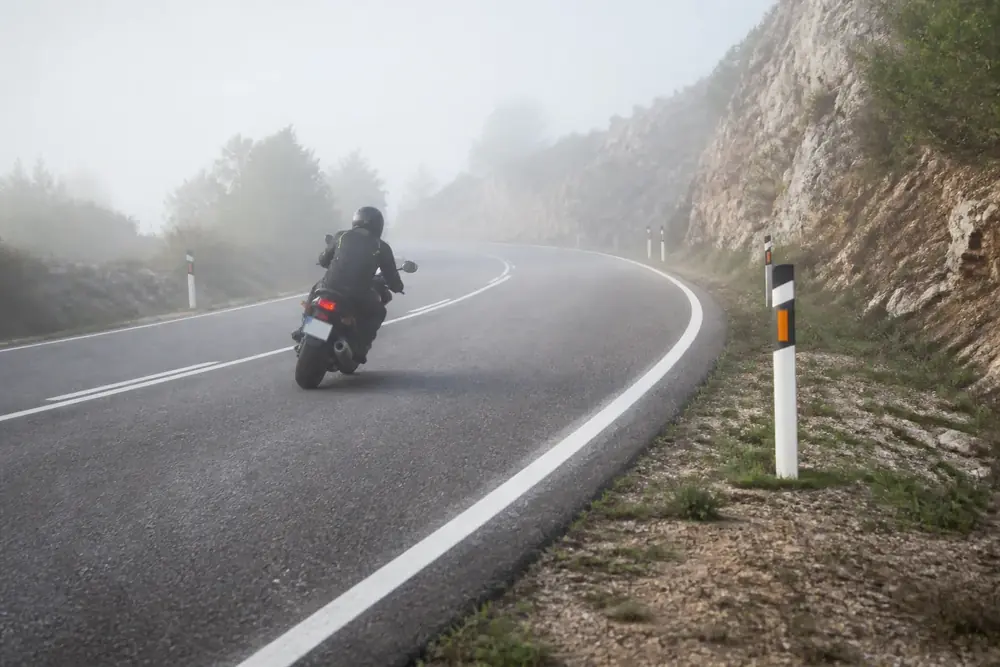 Motorista trazando una curva con niebla