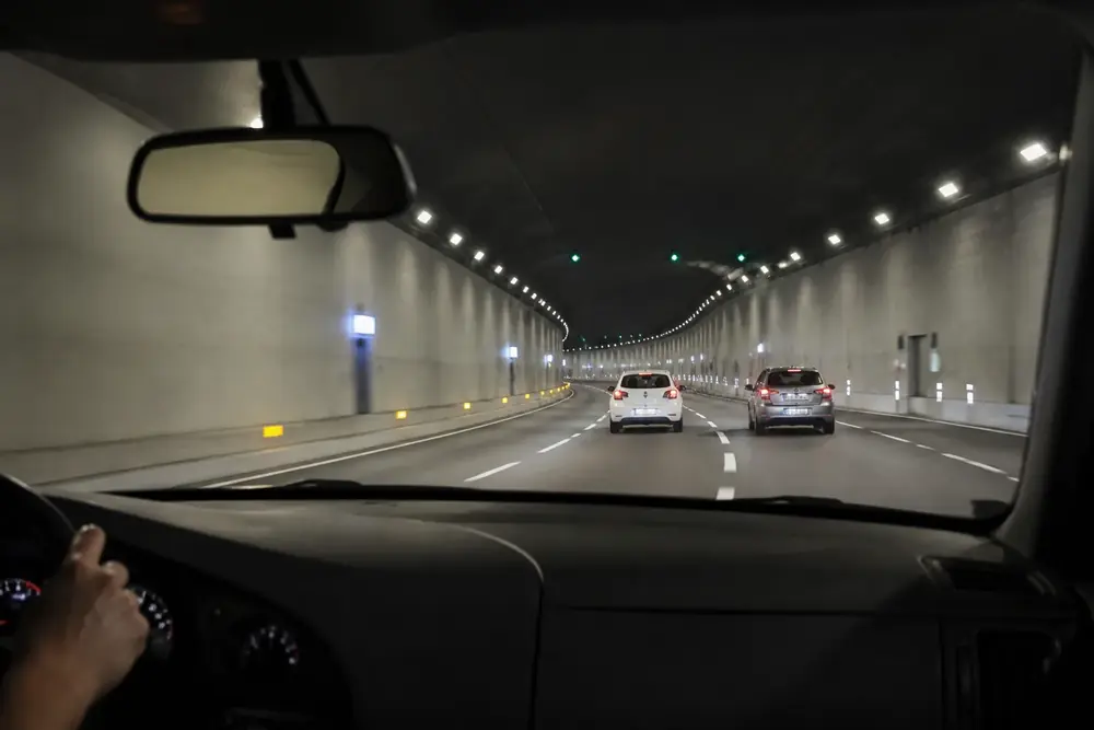 Interior de un túnel de autovía con dos vehículos por delante
