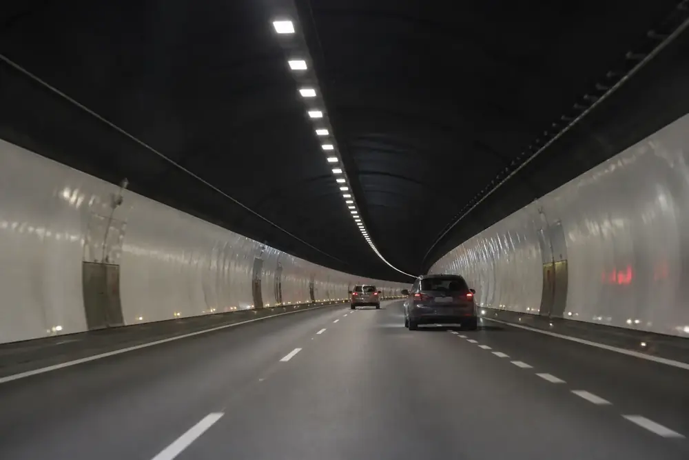Interior de un túnel de autovía con dos vehículos por delante
