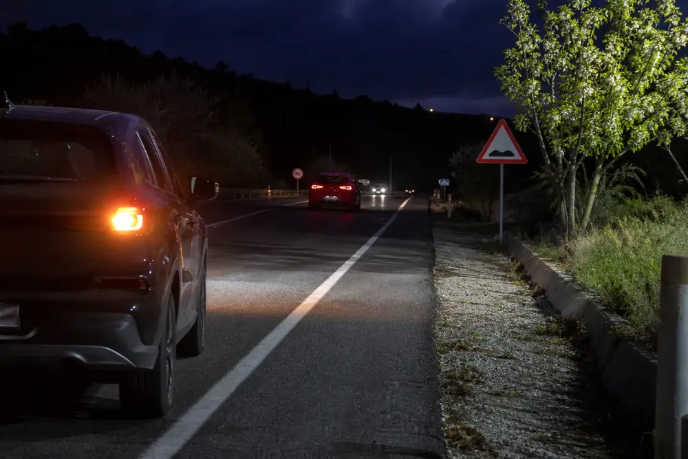Vehículo detenido de noche con las luces de emergencia encendidas