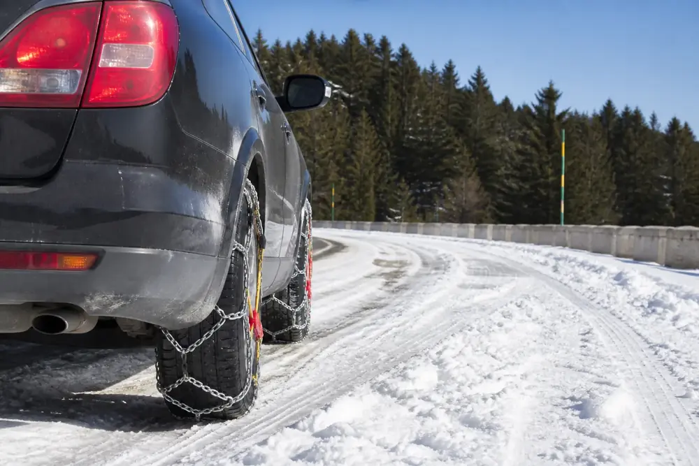Vehículo con cadenas montadas circulando por carretera nevada