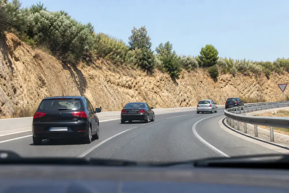 Carretera en curva con varios vehículos en fila