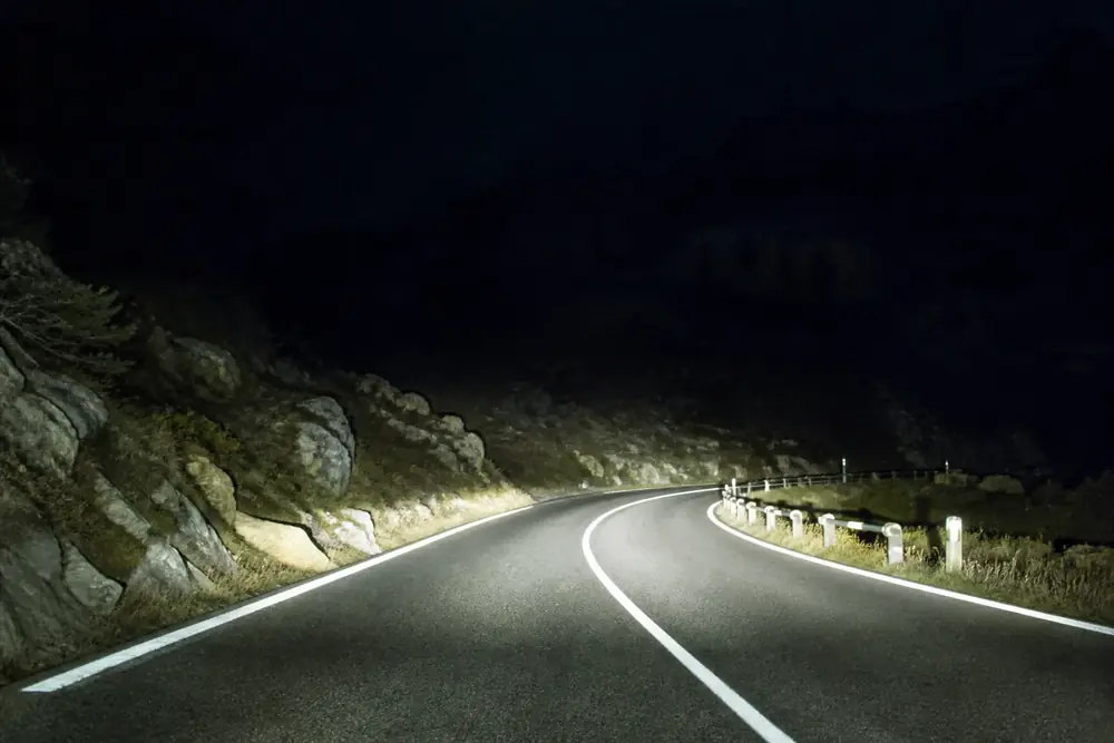 Carretera de montaña de noche iluminada por los faros
