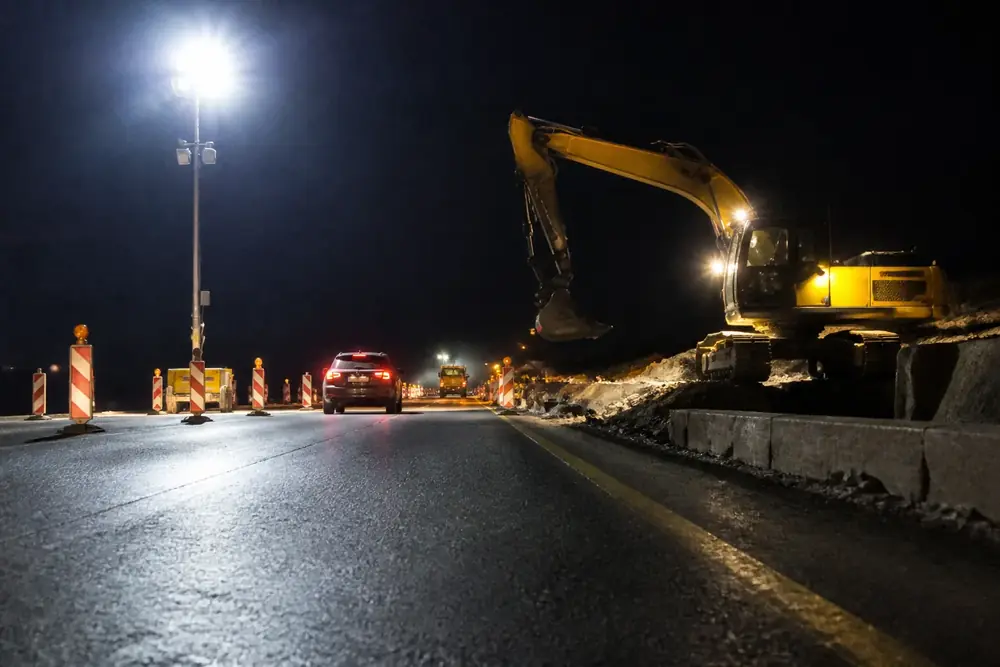 Obras nocturnas con excavadora y torres de iluminación