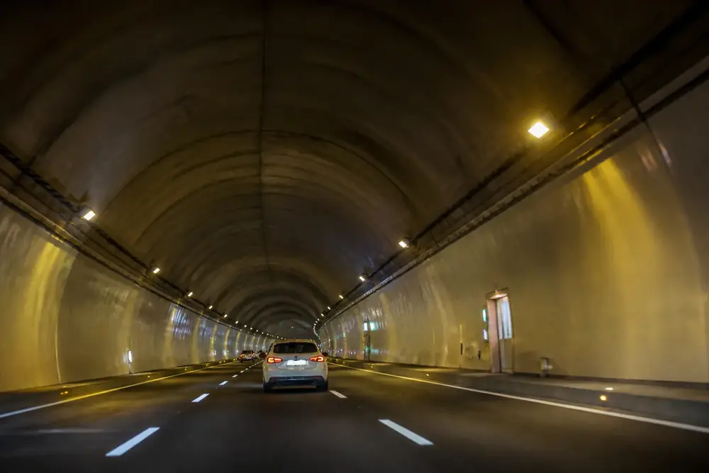 Interior de un túnel iluminado con un vehículo por delante