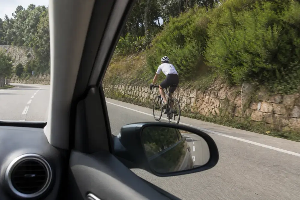 Ciclista visto por la ventanilla y el retrovisor desde el vehículo