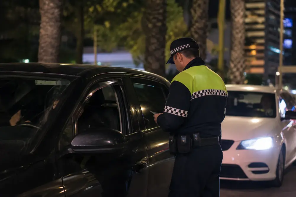 Agente junto a la ventanilla de un vehículo durante un control nocturno