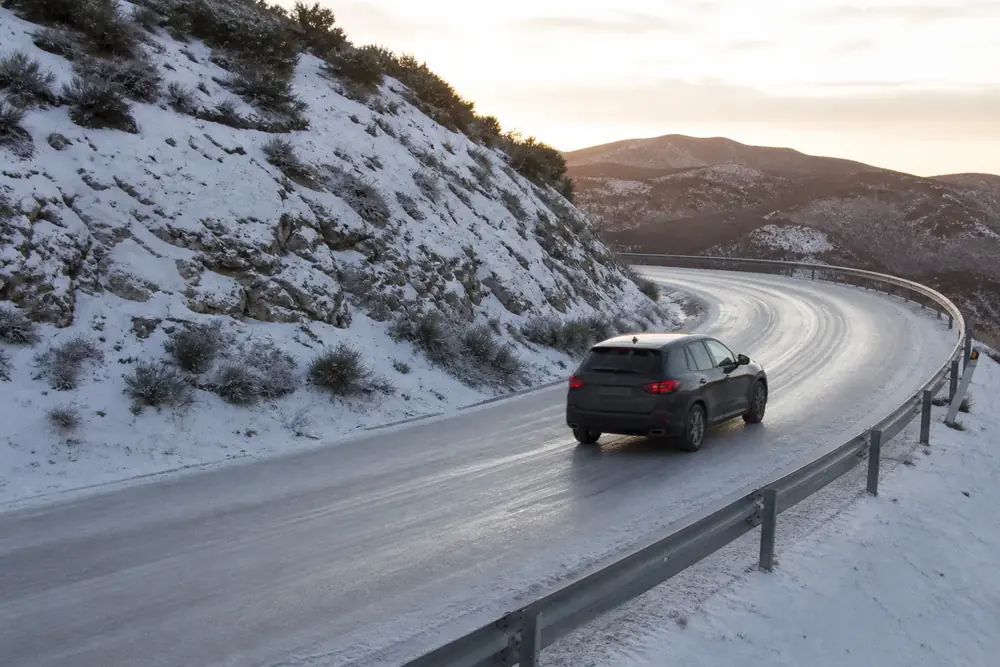 Turismo circulando por una carretera nevada de montaña