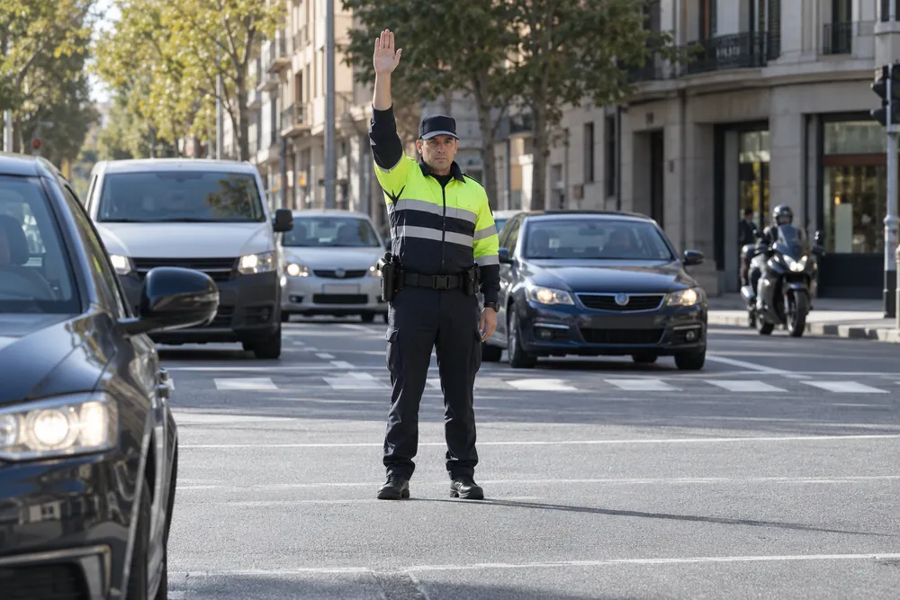 Agente de tráfico con un brazo levantado verticalmente.