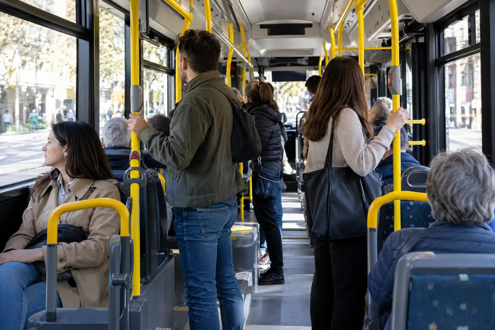 Viajeros de pie y sentados en un autobús urbano.