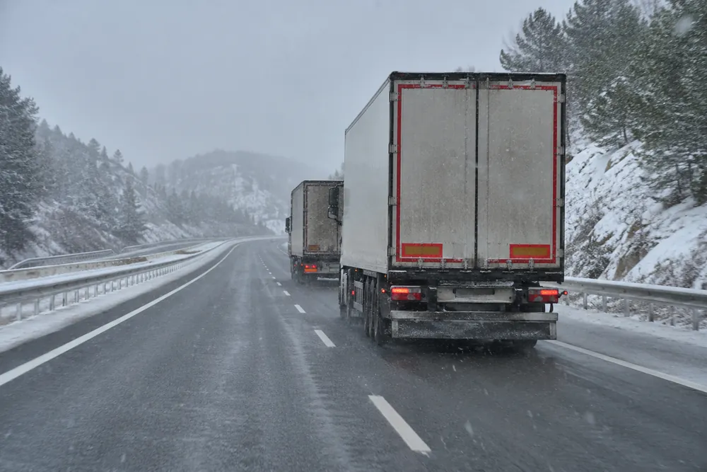 Camiones en una autovía con nieve.