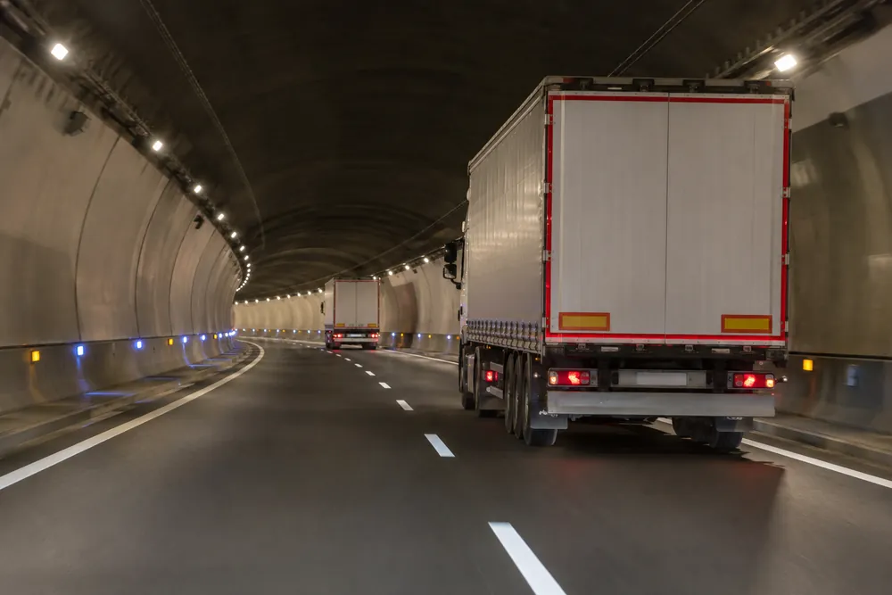 Camiones circulando separados dentro de un túnel.