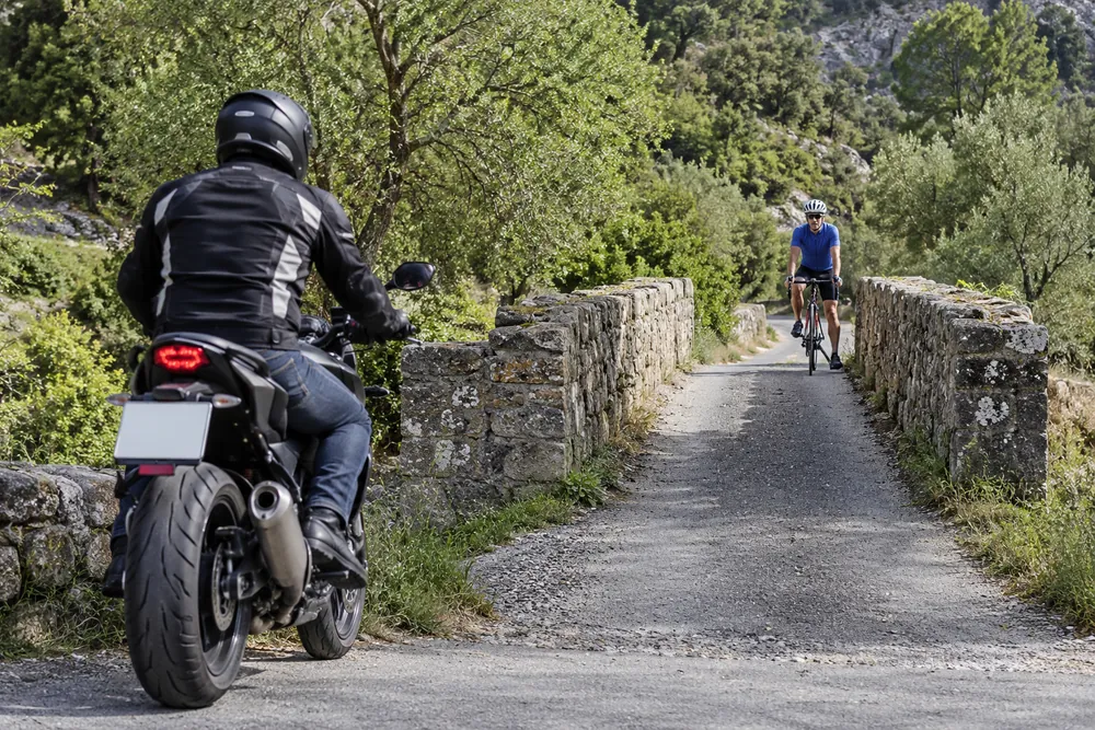 Motocicleta y bicicleta ante un paso estrecho.