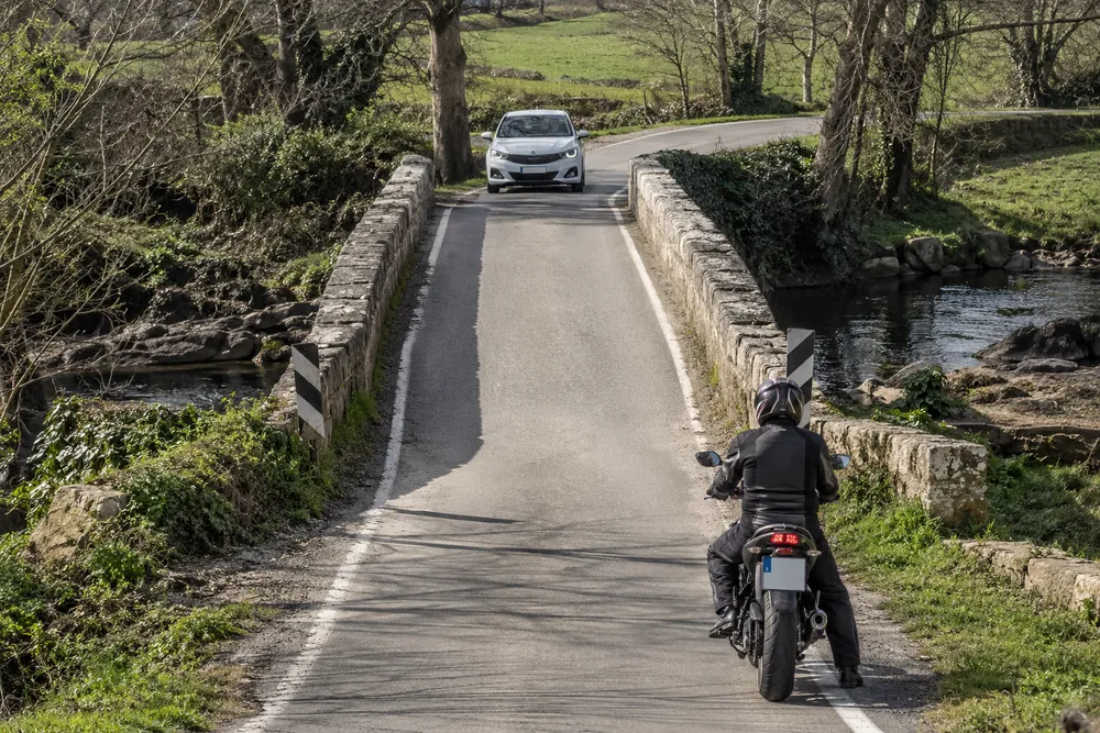Motocicleta y turismo ante un tramo estrecho.