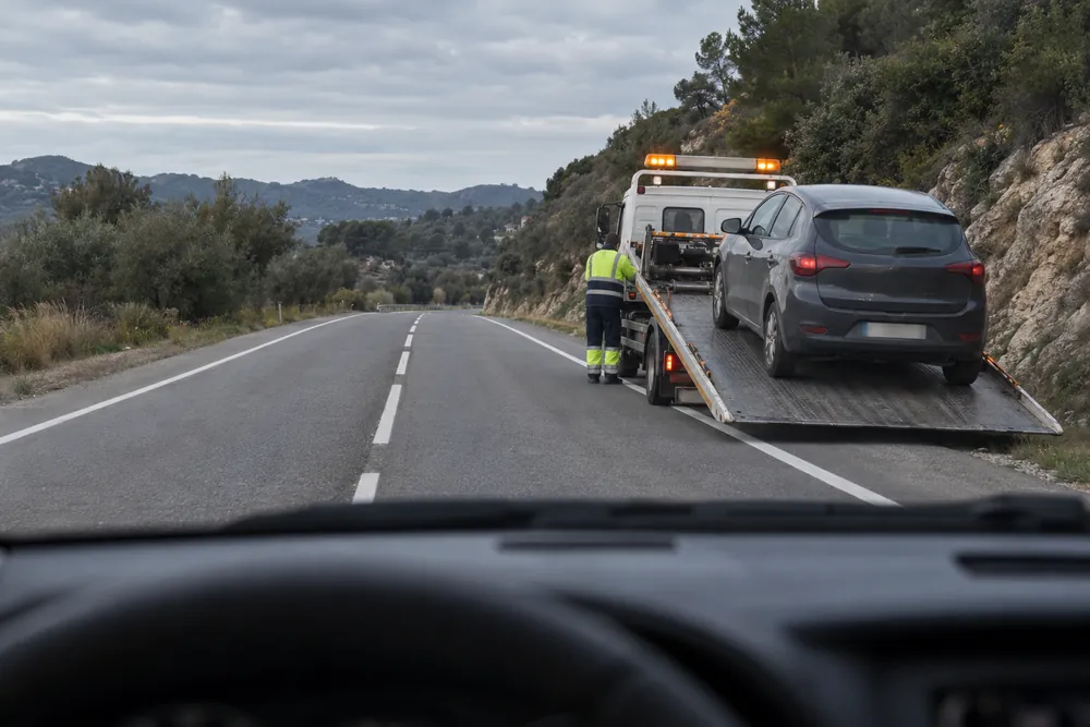 Grúa de asistencia cargando un vehículo averiado y ocupando parte de la calzada.