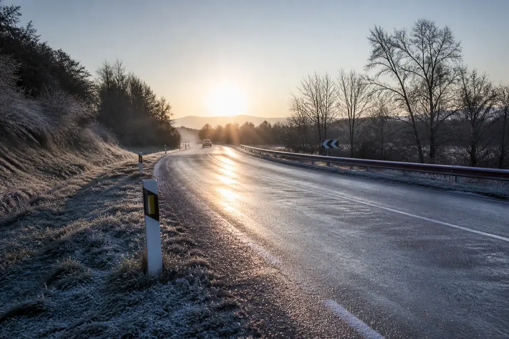 Placa de hielo brillante sobre el asfalto al amanecer